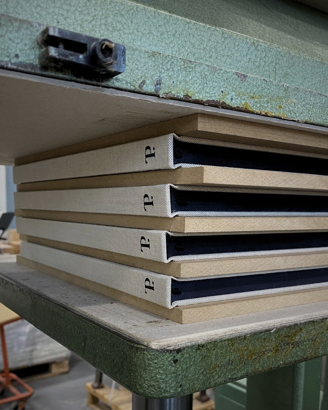 Stack of four The PLNR books in the pressing maching - The PLNR in the making. 